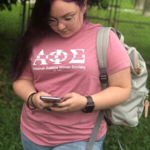 Person texting, wearing glasses and pink shirt.