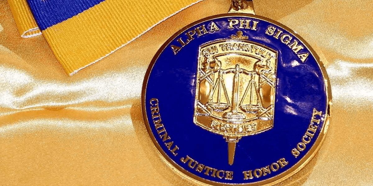 Alpha Phi Sigma honor society medallion on fabric.